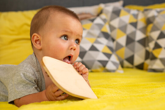 Infant Mouthing Wooden Activity Board During Floor Play