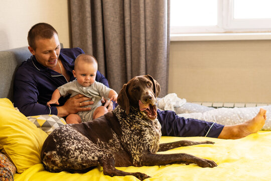 Father And Baby Son Relaxing With Family Dog