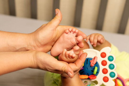 Mother Supporting Baby Son Feet During Gentle Massage