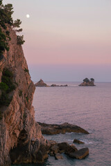 serene rocky coastline at dusk, high angle view of cliffs and calm sea with islands in the distance, natural landscape photography for travel and nature themes. © viktorbond
