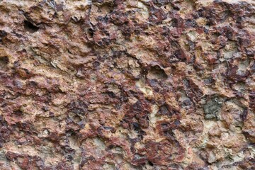 Fototapeta premium stone wall with pitted porous surface and reddish brown tone.