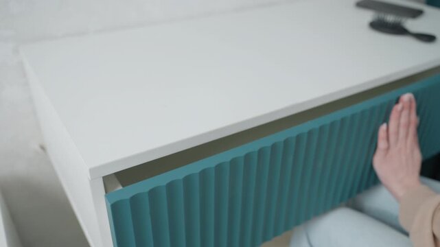 White desk teal drawer sliding hand preparing online coach prepping lesson props, fingers slide ribbed panel, reveal empty compartment, bright studio light, quick efficient movements, contemporary