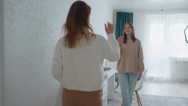 Calm home tutoring session with caucasian tutor, two women in bright bedroom workspace, soft light, casual clothing, sit and talk, teacher offers encouragement, grammar book and notes on desk, relaxed