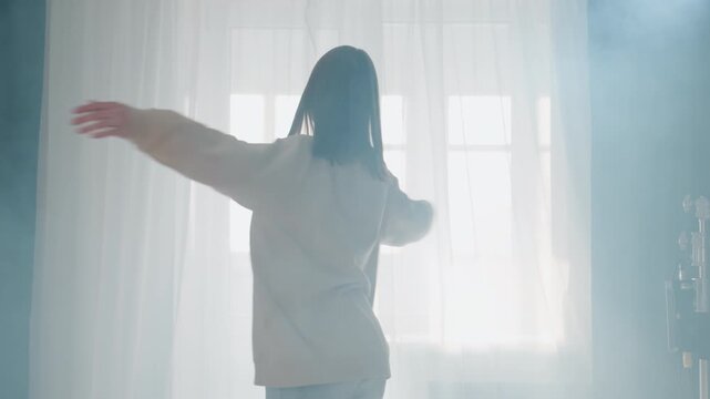 Caucasian dancer expressing joy through sweeping arm movements in bright room, spinning and reaching toward light, fluid gestures and uplifted posture, triumphant emotional release