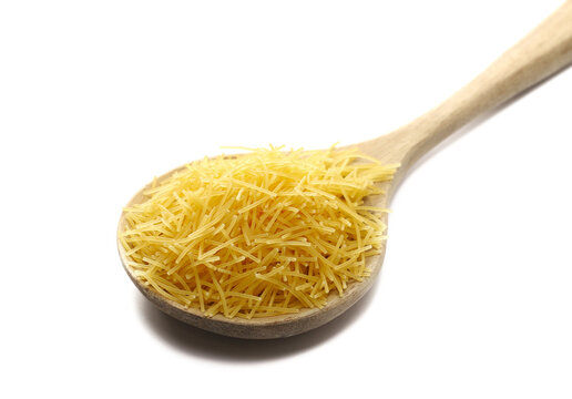 Uncooked durum wheat semolina pasta pile in wooden spoon isolated on white background, side view, vintage concept