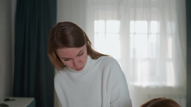 Experienced caucasian tutor reviews student answers with focused feedback, pen and paper evaluation at desk, natural window light, careful correction and positive reinforcement, lesson reflection