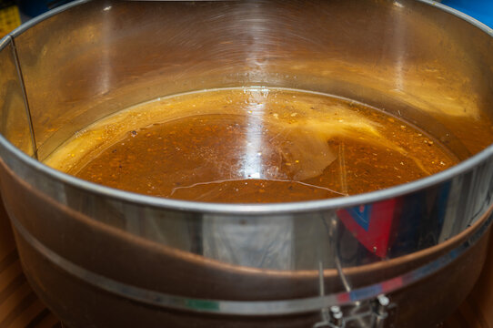 Freshly extracted raw honey filling a stainless steel container