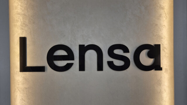 Black bold lettering spelling "Lensa" mounted on a textured, softly lit background wall. Picture taken on August 9, 2026 in Bucharest, Romania.