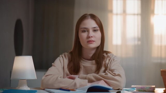 Young woman reading with determined effort tonight. Woman student studies diligently in quiet evening ambiance. Woman researcher concentrates intently on her textbooks under soft lamp light