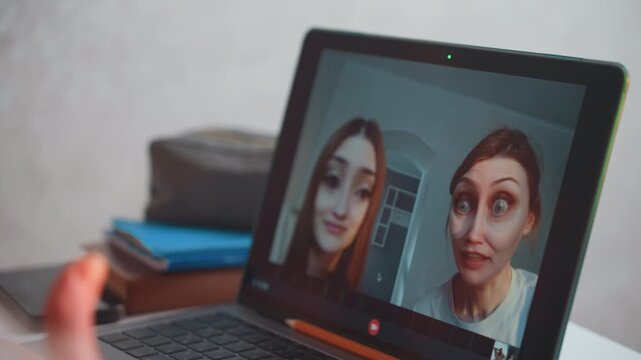 Online tutoring session white women laptop two white women interact via video call with playful face filter, student practicing grammar, coach guiding pronunciation, cozy home desk with notebooks