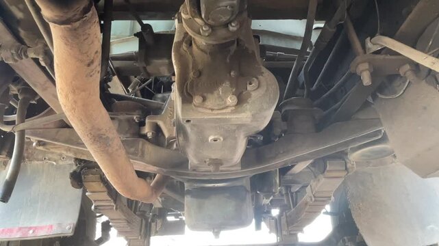 commercial truck exhaust pipes underbody systems during carwash process showing undercarriage chassis of heavy duty vehicle for cleaning maintenance inspection outdoor station.
