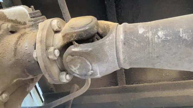 commercial truck universal joint driveshaft ujoint during carwash process showing undercarriage chassis of heavy duty vehicle for cleaning maintenance inspection outdoor station.