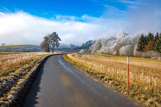 Winding country road through frosty fields on a sunny day