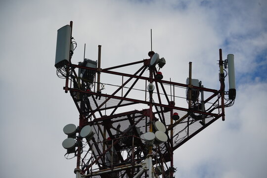 Horizontal close up of cell tower steel platform with mobile network sector panel antennas and microwave link dishes