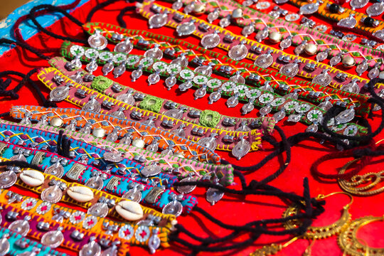 Assorted colorful handmade Indian bracelets, anklets and accessories decorated with metal charms, coins, bells and cowrie shells on display at a market in Hampi, India. Traditional ethnic fashion.