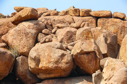Close-up of massive ancient orange granite boulders and rock formations in Hampi, India. Geological wonder, rugged terrain, natural stone background and historic landscape view texture.