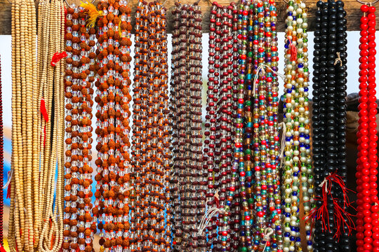 Assorted colorful hanging strings of traditional Indian prayer beads, japa mala and gemstone necklaces on display at a market stall in Hampi, India. Spiritual religious accessories collection.