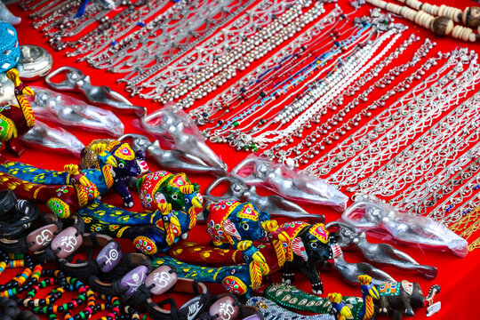 Assorted Indian handicrafts, traditional silver metal jewelry, ornate bracelets and colorful animal figurines on display at a market in Hampi, India. Ethnic souvenir shop merchandise collection.