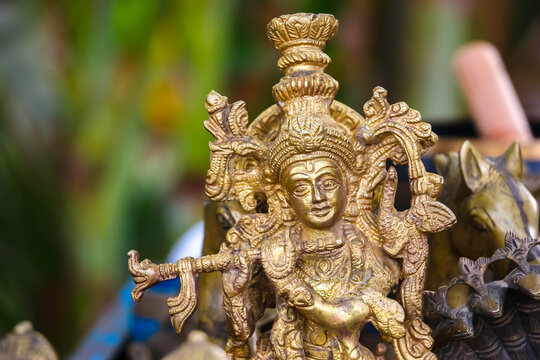 Ornate brass figurine of Hindu god Lord Krishna playing the flute on display at a market in Hampi, India. Traditional religious sculpture, spiritual art object and cultural heritage souvenir.