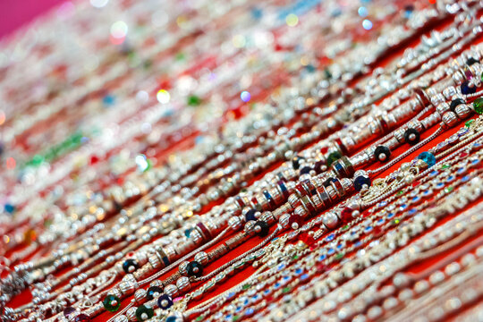 Traditional Indian silver metal jewelry necklaces and chains with colorful beads on display at a market in Hampi, India. Ethnic fashion accessories showcase, souvenir craft merchandise.