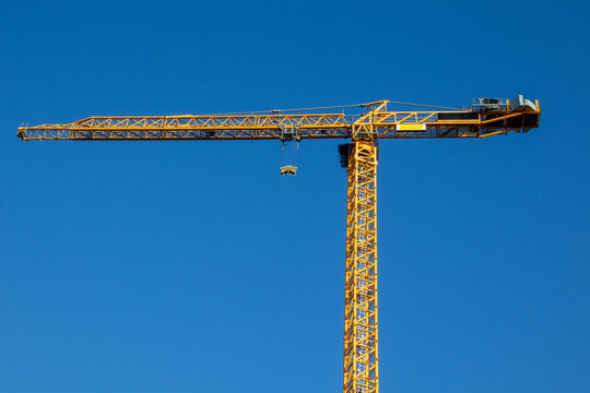 Tower crane full profile with jib and mast against clear blue sky