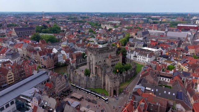 Aerial view video clip of medieval Gravensteen Castle, Leie river canal, city tram passing, historic guild houses, and city panorama in Ghent, East Flanders, Belgium