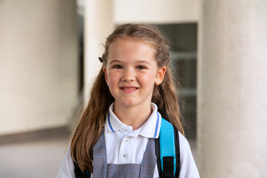 Young girl student smiling at campus wearing school uniform and backpack