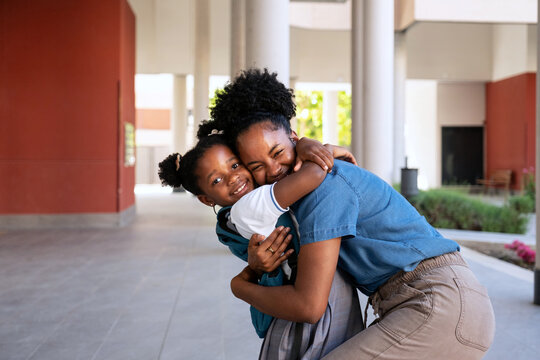 African American mother and daughter embracing with affection outdoors, returning to school