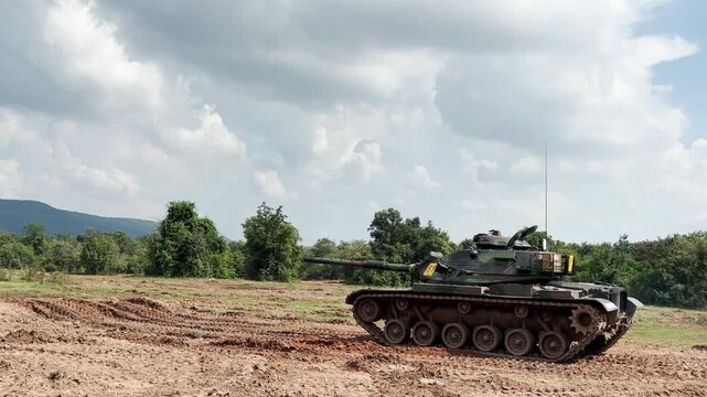 THAILAND - AUGUST 9, 2026: Heavy military battle tank operating in field training grounds, showing external armor tracks and interior tactical command cockpit equipment inside a restricted military zo