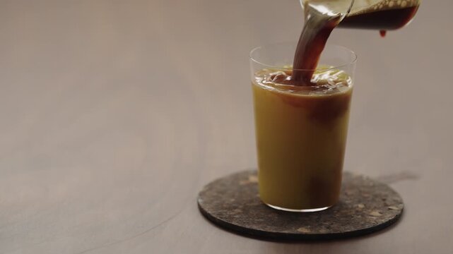 Slow motion pour espresso in glass with orange juice to make Bumble coffee