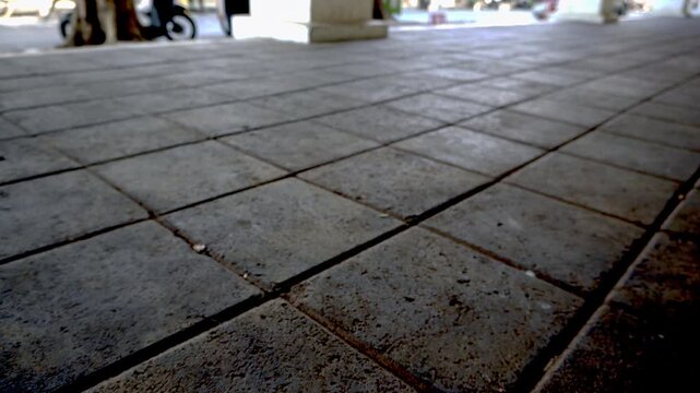 Static low angle shot of a clean paved stone tile floor walkway outdoors on a bright sunny day, showcasing texture and geometric perspective lines.