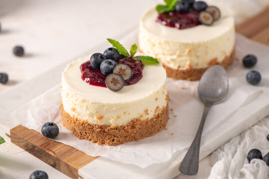 Mini cheesecakes with fresh blueberries and berry compote on a marble board