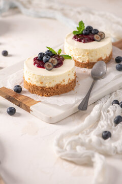 Mini cheesecakes with fresh blueberries and berry compote on a marble board