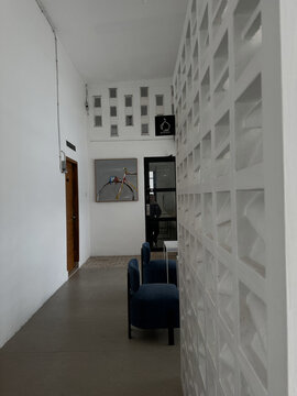 Modern minimalist corridor interior with white breeze block wall partition and blue lounge chairs