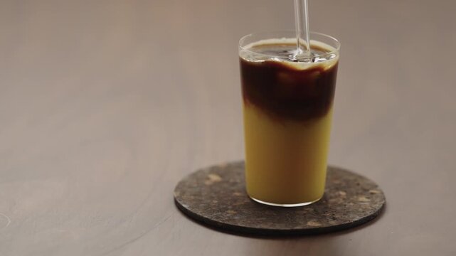 Slow motion taking a sip of bumble coffee with a glass straw