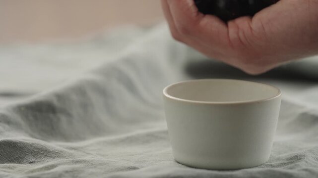 Slow motion man hand put washed ripe blackcurrant in ceramic bowl