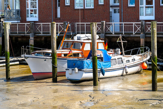 Husum, Germany. Two moored leisure boats rest on the mud during low tide in the harbor of Husum, illustrating the tidal character of Germany's North Sea coast.