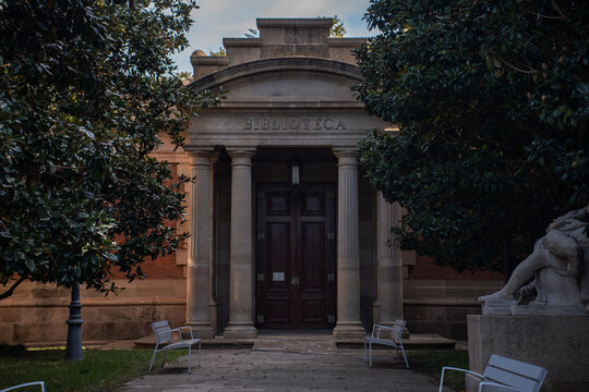 Historic classic library building entrance facade with stone columns and wooden door.
