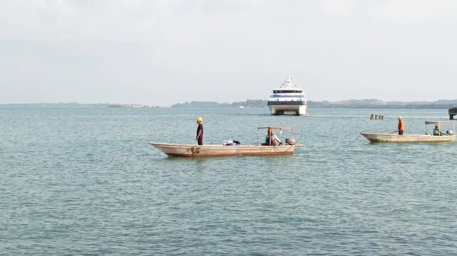 Footage of a large passenger ferry ship and small wooden boats on calm sea during daytime.