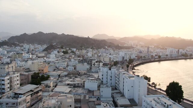 Muscat waterfront cityscape surrounded by rugged mountains at sunset, old Muscat view from muttrah fort in Oman