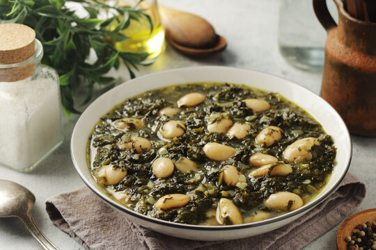 A bowl with traditional Tuscan kale salad and white beans soup Cavolo nero e fagioli