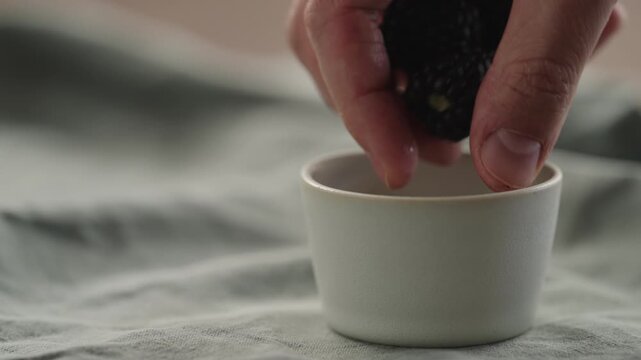 Slow motion man hand put fresh ripe blackberry in a white small bowl