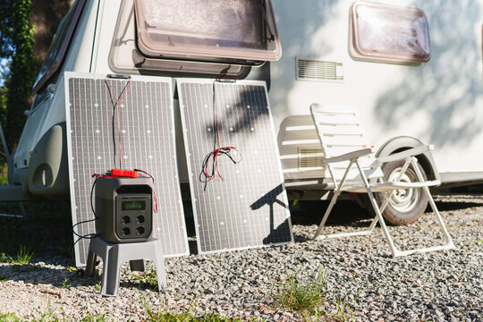 Portable power station with solar panels near a travel trailer caravan