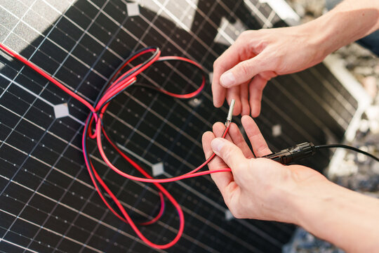 Close-up of technician hands connecting MC4 cables to a solar panel