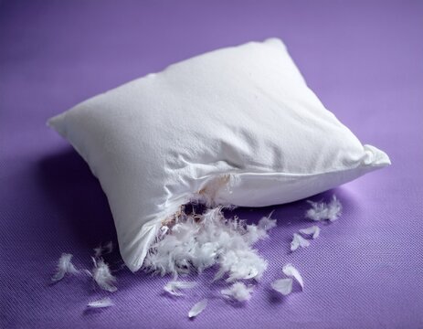 soft white pillow with visible tear and exposed fluffy stuffing spilling onto pastel lavender surface showing fabric texture and soft filling for repair home comfort and bedding use