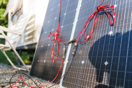 Close-up of flexible solar panels with cables near a travel trailer caravan