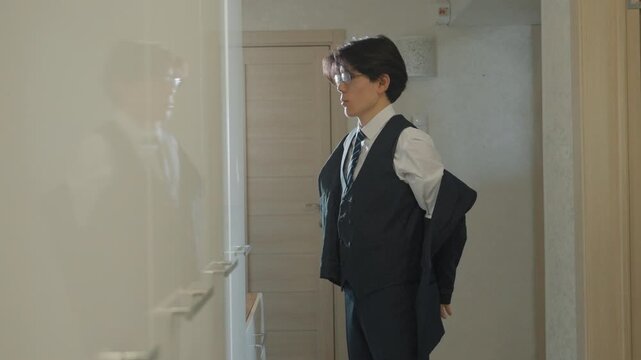 Candidate gets ready silently. Asian man adjusts clothing quietly. Young male readies himself calmly before interview. Asian male calmly prepares in corridor prior to interview session