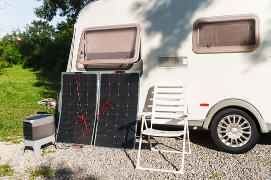 Portable power station with solar panels near a travel trailer caravan
