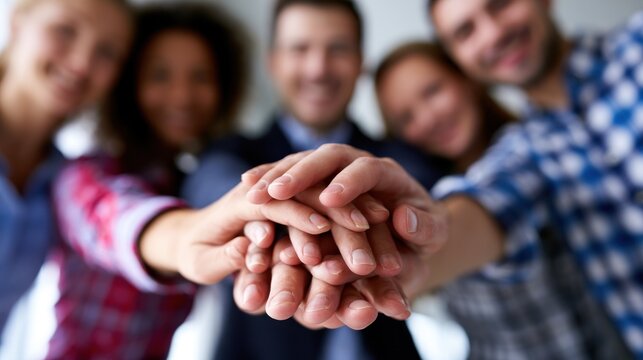 Group of colleagues smiling and stacking hands as a gesture of teamwork and unity in the office