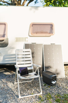 Portable power station with solar panel charging gadgets near a travel trailer caravan